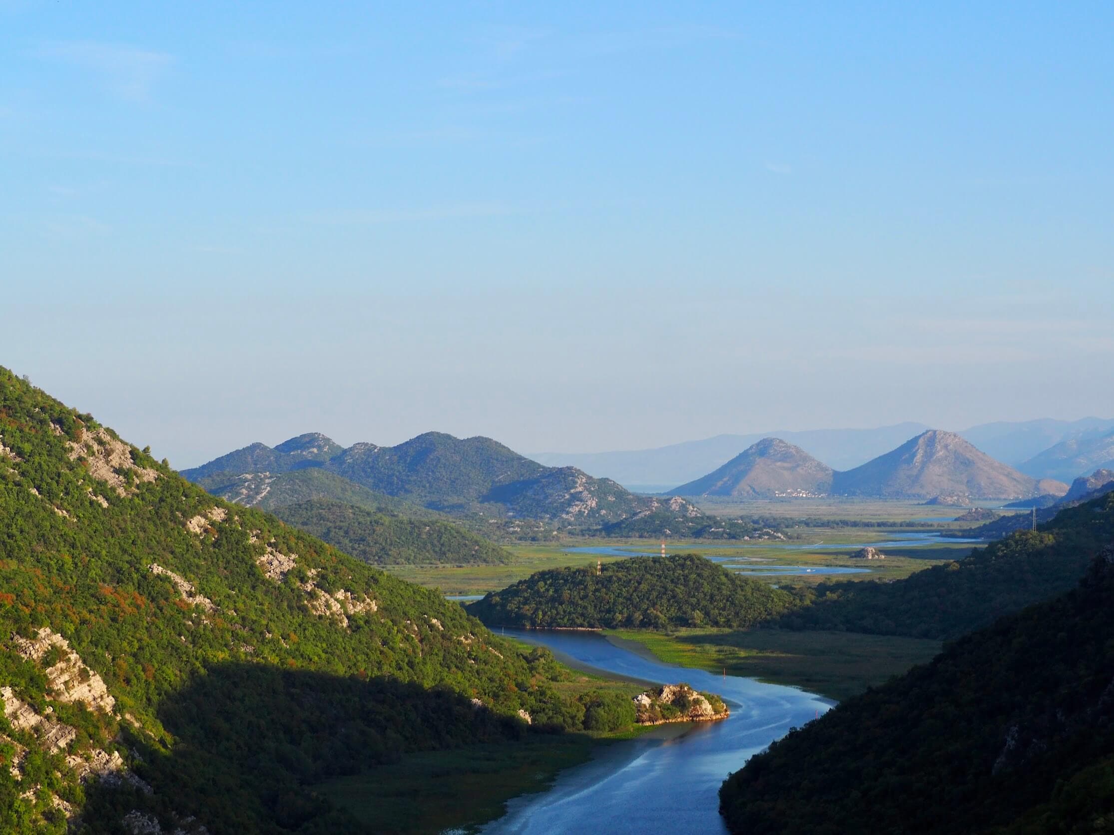 Colline boisée se reflétant dans les eaux paisibles du lac Skadar, au Monténégro